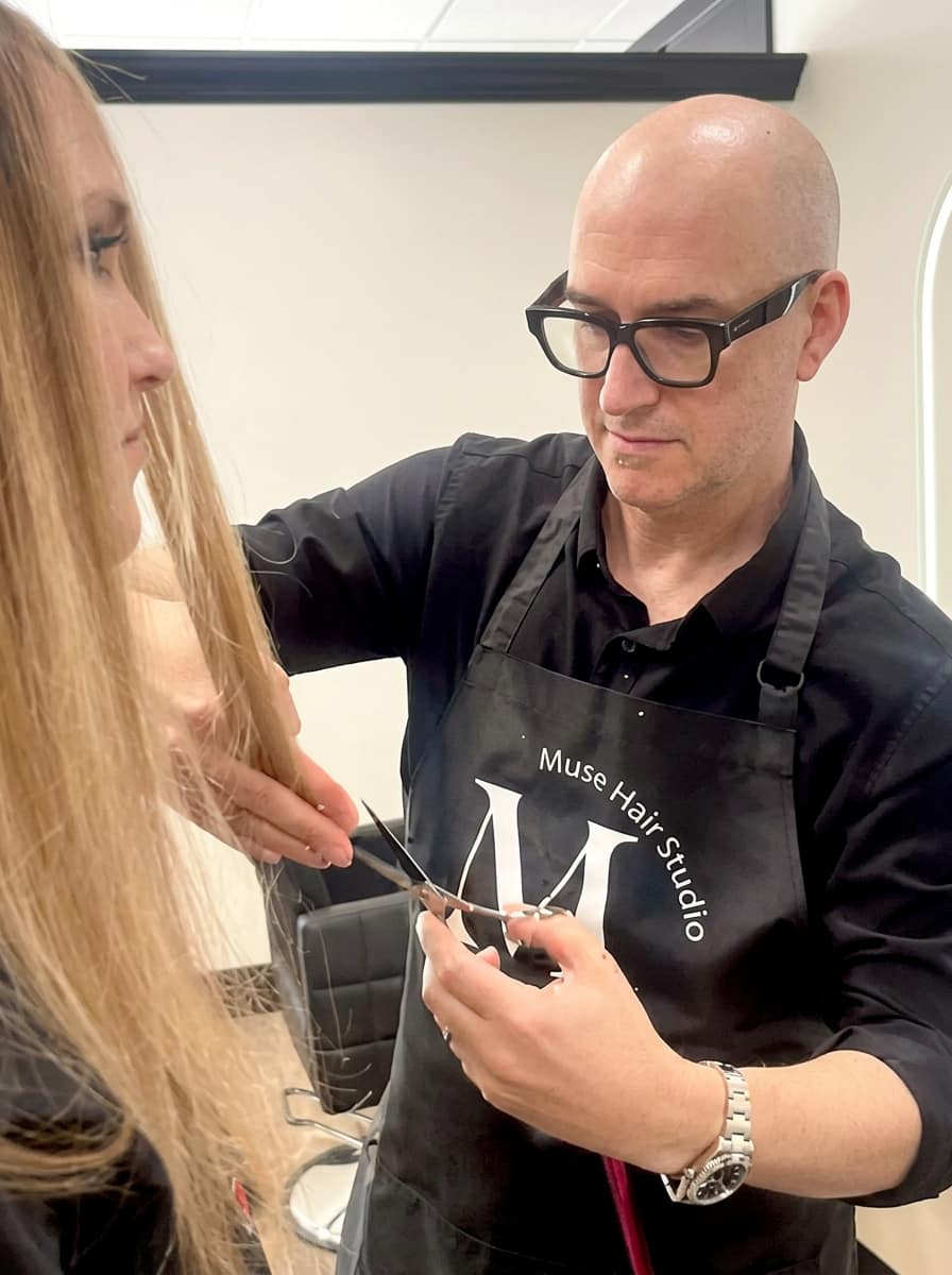 Stylist wearing a Muse Hair Studio branded apron mid-cut