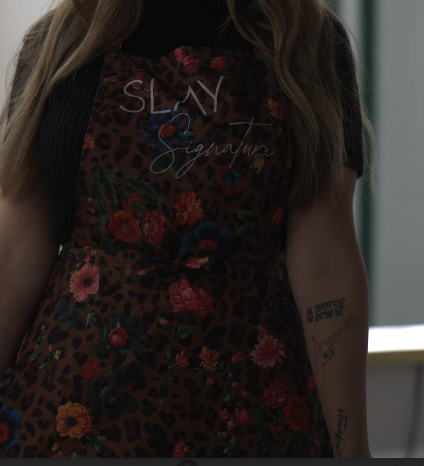 Stylist in a custom Slay Signature floral leopard print apron